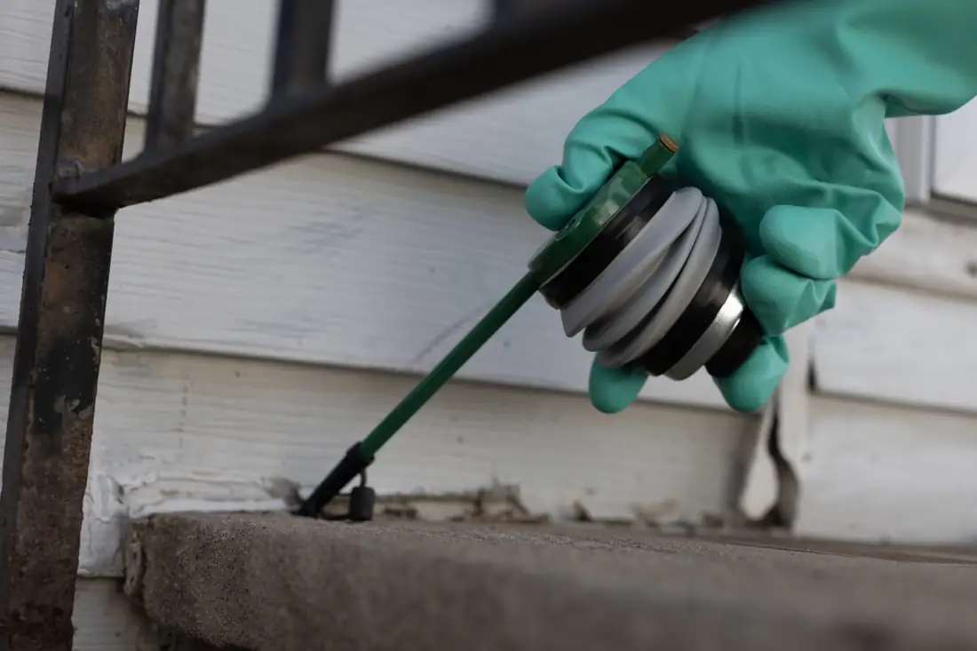 Gloved hand dusting a gap in vinyl siding