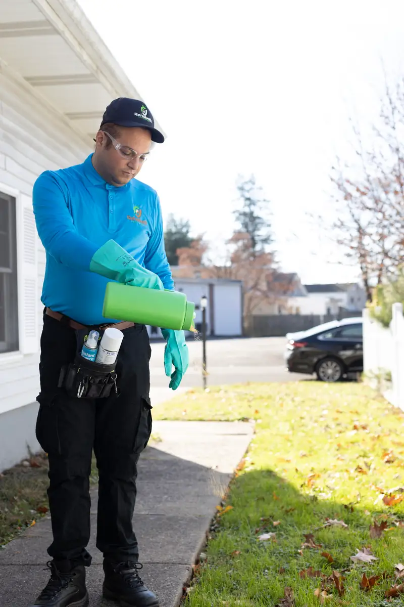 Technician with a bellows duster beside a house