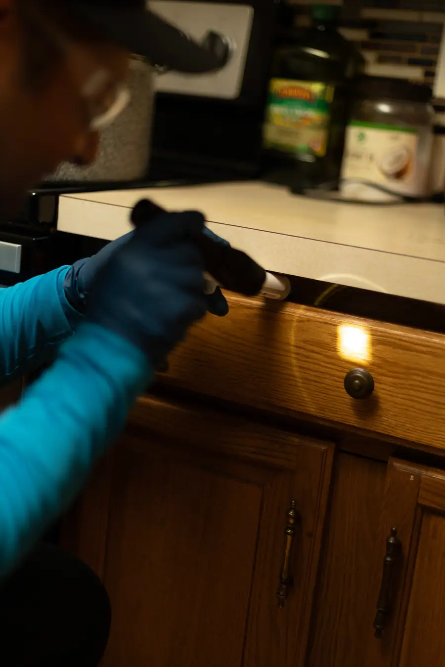Technician inspecting kitchen cabinet gaps with a flashlight