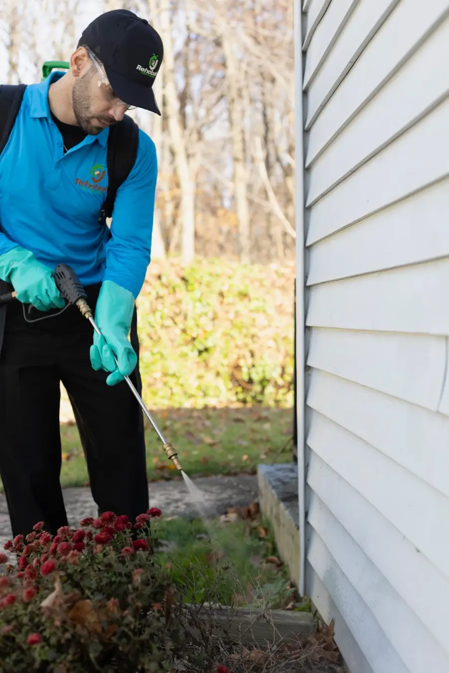 Technician spraying a perimeter treatment along a home's foundation